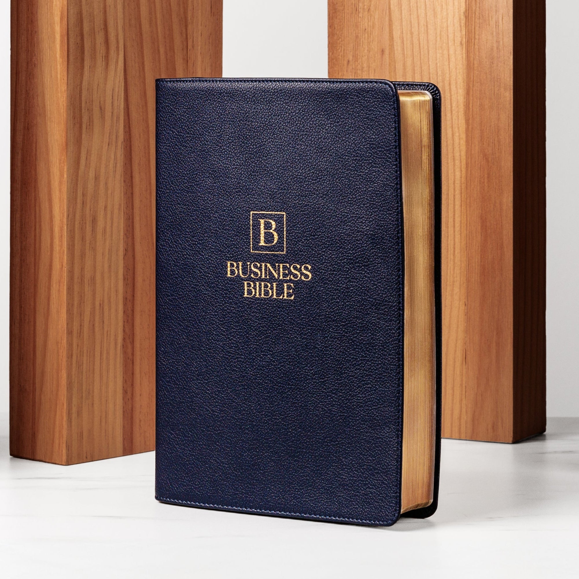 A navy blue Bible with gold lettering on the cover, titled 'BUSINESS BIBLE', displayed against a wooden background.