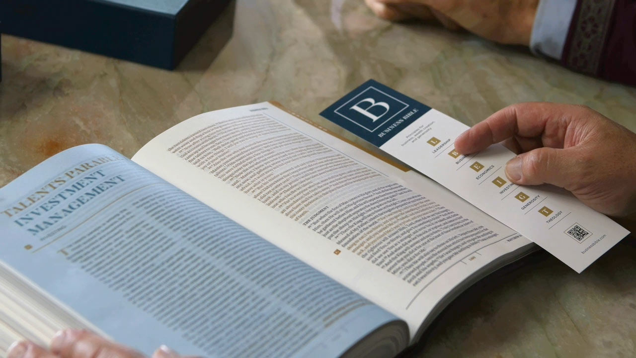 Hand turning pages of a business principles and economics book